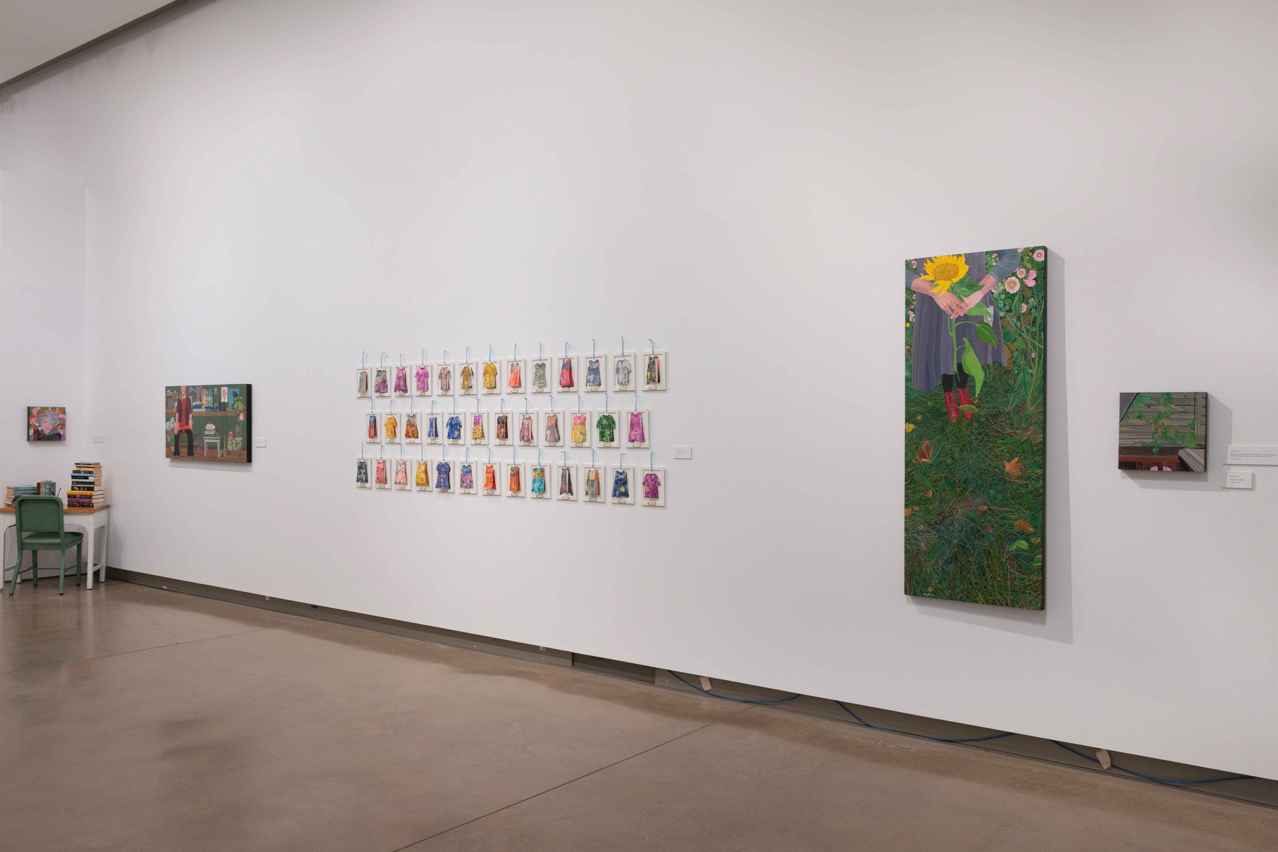 Installation view of watercolour grid of dresses flanked by paintings on either side