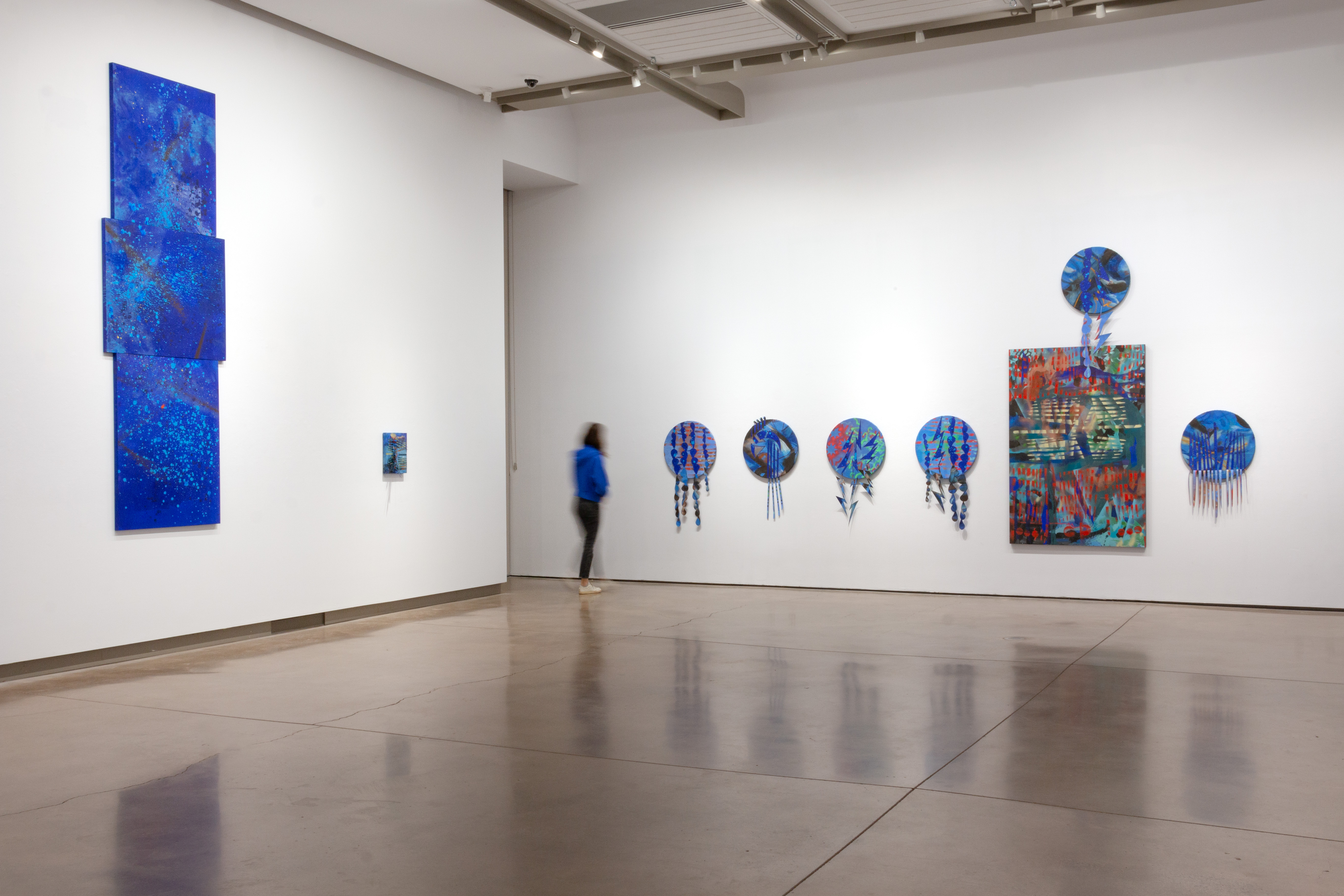blue paintings at various heights in a white room